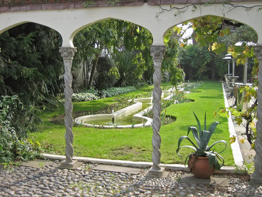 Patio con arcos, césped y plantas